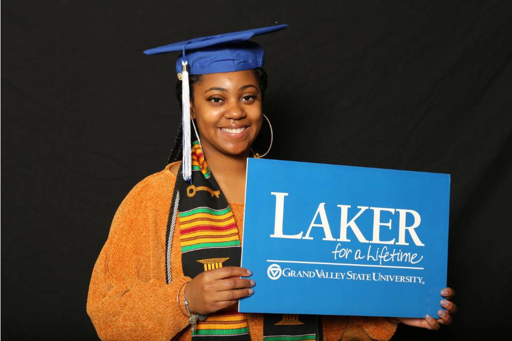 woman in graduation cap holding laker for a lifetime sign